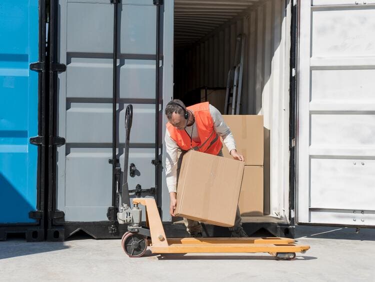 Homem organizando caixas dentro do container